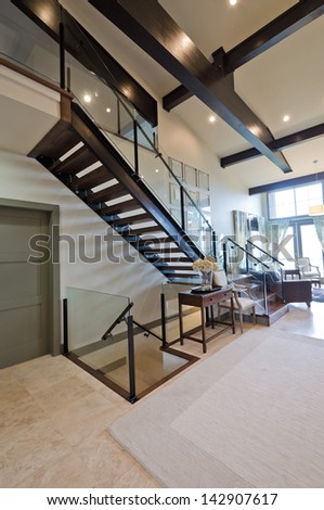 Outlook at the luxury spacious modern living room with the stairs to the upper level. Interior design. Vertical.