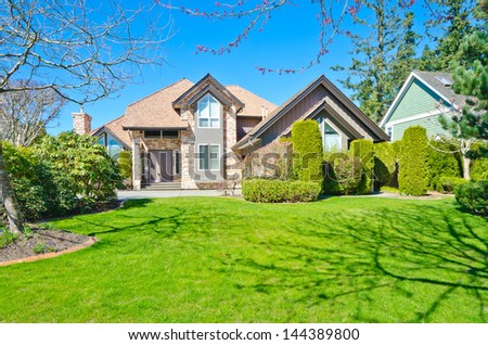 Big custom made luxury house with nicely trimmed and landscaped front yard lawn in the suburbs of Vancouver, Canada.