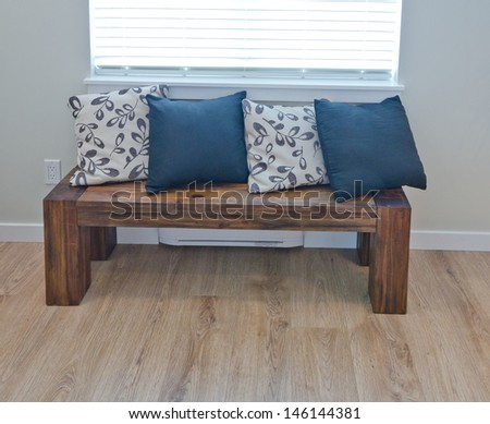 Decorative wooden bench with some pillows on it as an element of the interior design.