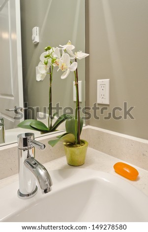 Nicely decorated modern washroom with the sink and vase with flowers, orchid. Interior design. Vertical.