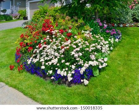 Nicely decorated colorful flowerbed and trimmed front yard lawn. Landscape design.