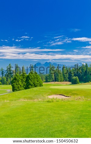 Sand bunker at the beautiful golf course with a mountains and dark blue sky. Vertical. Vancouver, Canada.