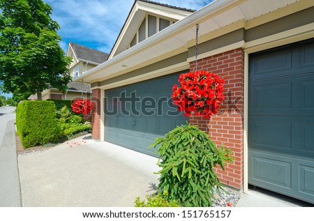 House with double doors garage and hanging buckets with flowers in the suburbs of Vancouver, Canada.