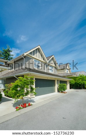 Nice neighborhood. Houses with double doors garages on the empty street in the suburbs of Vancouver, Canada. Vertical.