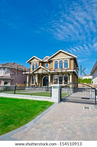 Big custom made luxury house with long driveway and metal gates in the suburbs of Vancouver, Canada. Vertical.