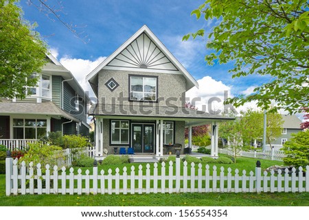 House behind county style wooden fence and nicely trimmed front yard lawn.