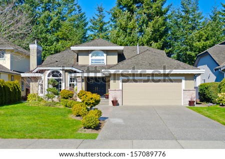 Big custom made luxury house with double doors garage and long driveway and nicely trimmed and landscaped front yard lawn in the suburbs of Vancouver, Canada.