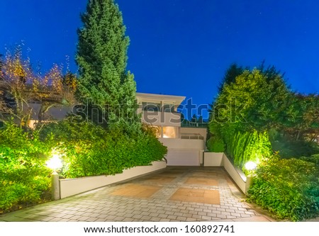 Long nicely paved driveway to garage of the big luxury house at dusk, night time in suburbs of Vancouver, Canada.