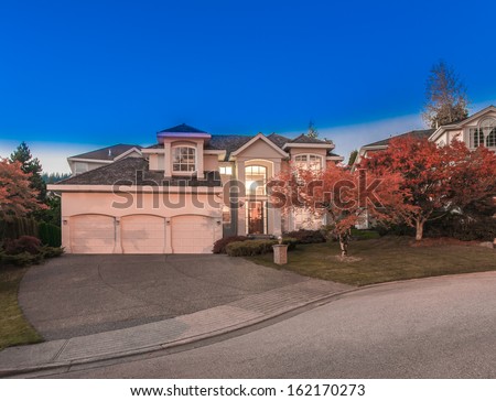 Big luxury house with triple garage at night, disk, sunset, sunrise time in suburbs of Vancouver, Canada.