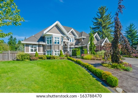 Big custom made luxury house with nicely trimmed and landscaped front yard lawn in the suburbs of Vancouver, Canada.