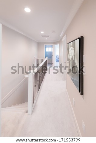 A corridor on the upper level of a house with the stairs and the rooms at the end. Interior design.