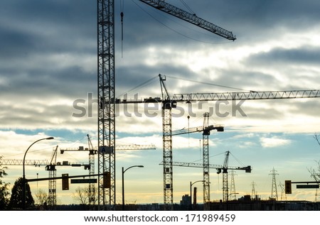 Construction site with cranes at sunset, sunrise, dawn time with the cranes as a silhouette. Vancouver, Canada.
