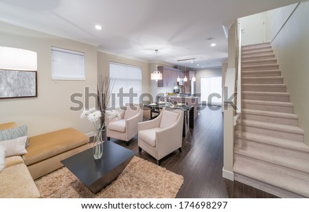 Outlook at the luxury modern living suite : living room, dining room and the kitchen at the back with two modern chairs in front of. Interior design of a brand new townhouse.