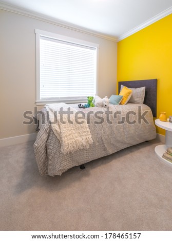 Modern comfortable, nicely decorated children bedroom painted in yellow. Interior design.