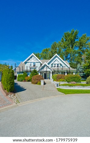 Big custom made luxury house with nicely landscaped front yard and long and wide nicely paved driveway in the suburbs of Vancouver, Canada. Vertical.
