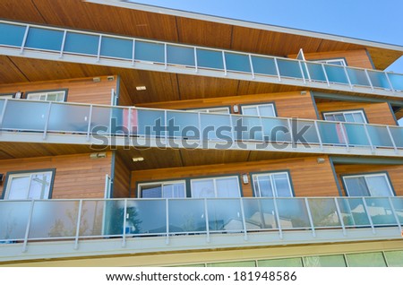Perspective, outlook of the modern glass, wood and steel building, house with the balconies on perimeter.  Exterior design.