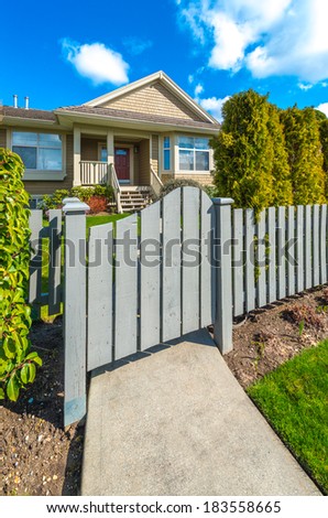 Country style long wooden fence with the gate, wicket and a house behind. Country style long wooden fence with nicely trimmed grass. Vertical.