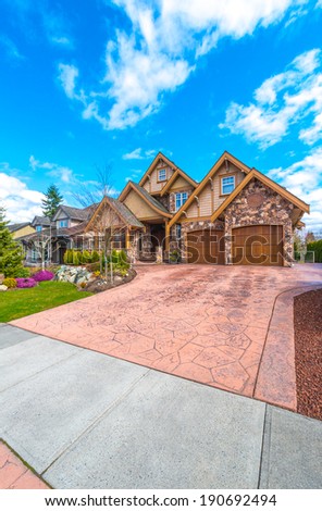 Big custom made luxury house with nicely paved driveway to the double doors garage  in the suburbs of Vancouver, Canada. Vertical.