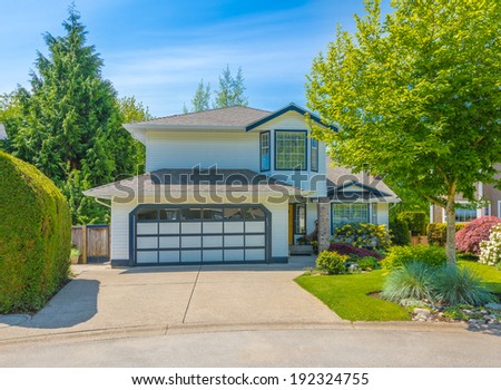 Custom built luxury house with nicely trimmed front yard, lawn and wide driveway to the double doors garage in a residential neighborhood. Vancouver Canada.