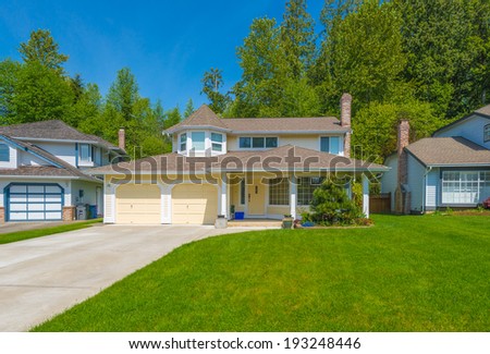 Custom built luxury house with nicely trimmed front yard, lawn and long driveway in a residential neighborhood. Vancouver Canada.