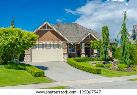 Big custom made luxury house with nicely landscaped front yard and long and wide driveway to garage in the suburb of Vancouver, Canada.