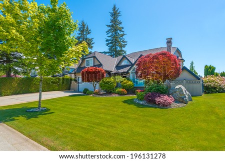Custom built luxury house with nicely trimmed front yard, lawn in a residential neighborhood. Vancouver, Canada.