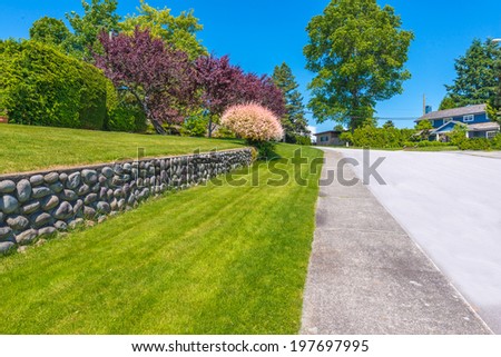 Some flowers and nicely trimmed bushes on the leveled and stoned front yard. Landscape design.