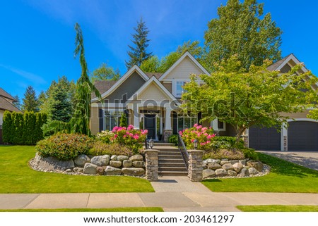 Big custom made luxury house with nicely trimmed and  landscaped front yard and steps and stones to the entrance  in the suburb of Vancouver, Canada.