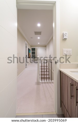 Corridor on the upper level of a house with the stairs and the room at the end. Interior design.