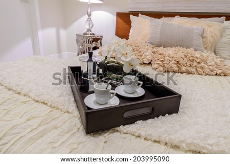 Decorative tray with the coffee set on the bed in the luxury master bedroom. Interior design.