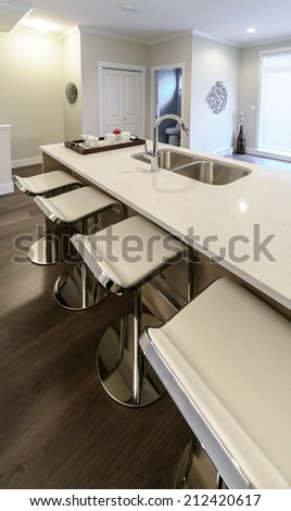 Interior design of a luxury modern kitchen with some sits in a bar style at the island counter. Vertical.