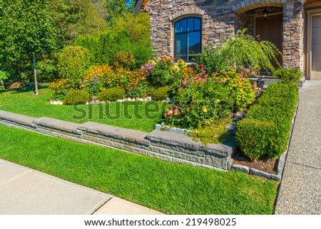 Nicely decorated colorful flowerbed and trimmed bushes at front yard lawn in front of the house. Landscape design.
