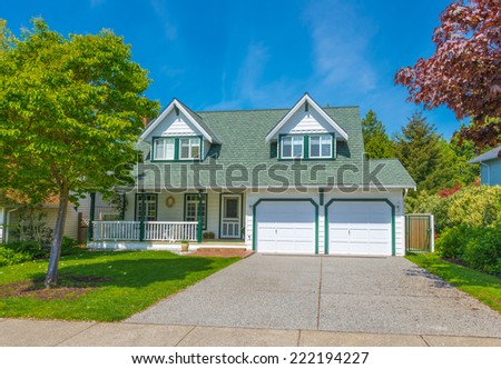 Custom built luxury house with nicely trimmed front yard, and driveway to the double doors garage in a residential neighborhood. Vancouver. Canada.