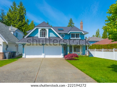 Custom built luxury house with nicely trimmed front yard, and driveway to the double doors garage in a residential neighborhood. Vancouver. Canada.