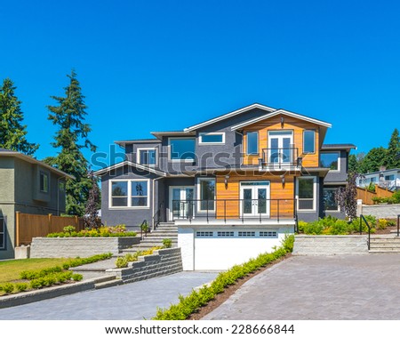 Big custom made luxury modern house with nicely landscaped  front yard and paved driveway to garage in the suburbs of Vancouver, Canada.