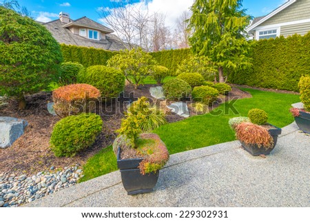 Nicely trimmed and landscaped front, back yard. Flowers and stones in front of the house, front yard. Landscape design.