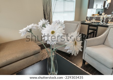Some flowers in the vase on the coffee table  and the dining room at the back. Interior design of a brand new house.