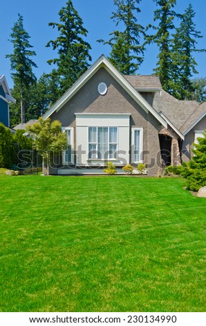 Fragment of a custom built luxury house with nicely trimmed and landscaped front yard lawn in a residential neighborhood. Vancouver Canada. Vertical.