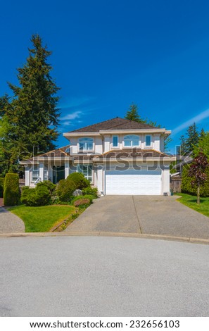 Custom built luxury house with nicely trimmed front yard, lawn and driveway to garage in a residential neighborhood. Vancouver Canada. Vertical.