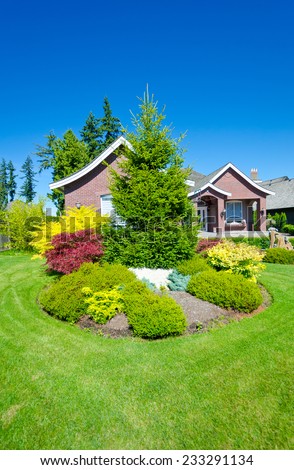 Flowers and stones and nicely trimmed bushes in front of the house, front yard. Landscape design.