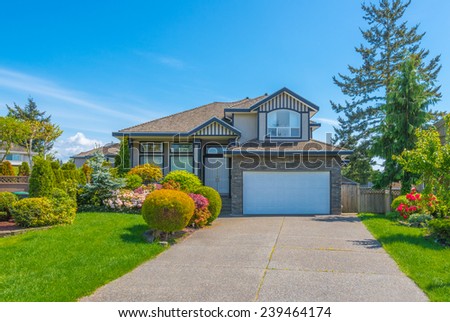 Custom built luxury house with nicely trimmed and landscaped front yard, lawn and wide driveway to the garage in a residential neighborhood. Vancouver Canada.