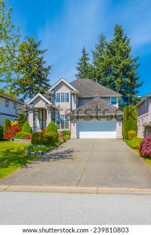 Custom built luxury house with nicely trimmed and landscaped front yard, lawn and wide driveway to the garage in a residential neighborhood. Vancouver Canada. Vertical.