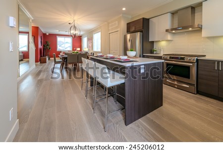 Nicely decorated kitchen counter table, iceland table and dining table and living room at the back. Interior design.