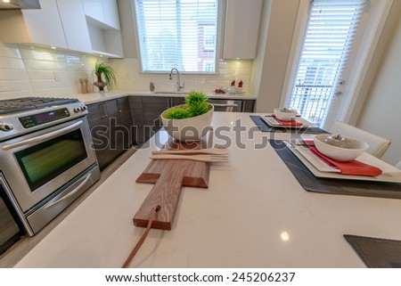 Nicely decorated kitchen counter, table with bowl with some green salad on the cutting deck and the kitchen at the back. Interior design.