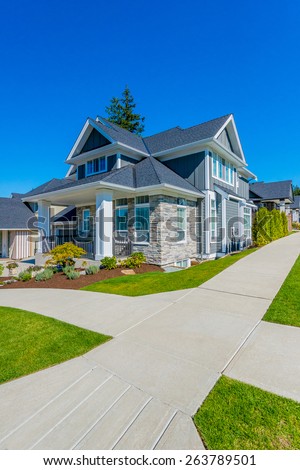Big custom made luxury house with nicely landscaped front yard and driveway to garage in the suburb of Vancouver, Canada. Vertical.