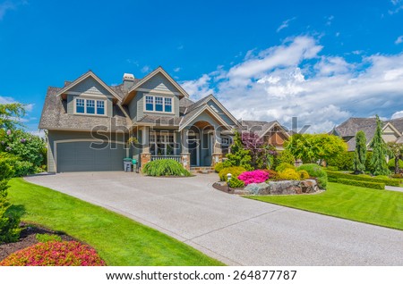 Big custom made luxury house with nicely landscaped front yard and driveway to garage in the suburb of Vancouver, Canada.
