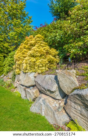 Flowers and stones in front of the house, front yard. Landscape design. Vertical.