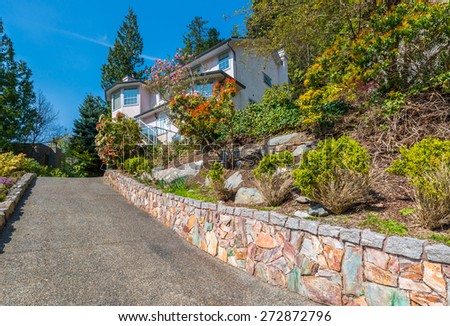 Big custom made luxury house with nicely landscaped front yard and long driveway to garage in the suburbs of Vancouver, Canada.