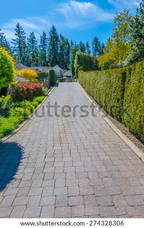 Paved driveway to the  custom made luxury house with nicely landscaped and trimmed front yard in the suburbs of Vancouver, Canada. Vertical.