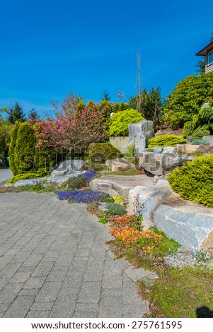 Flowers and stones in front of the house, front yard. Landscape design. Vertical.